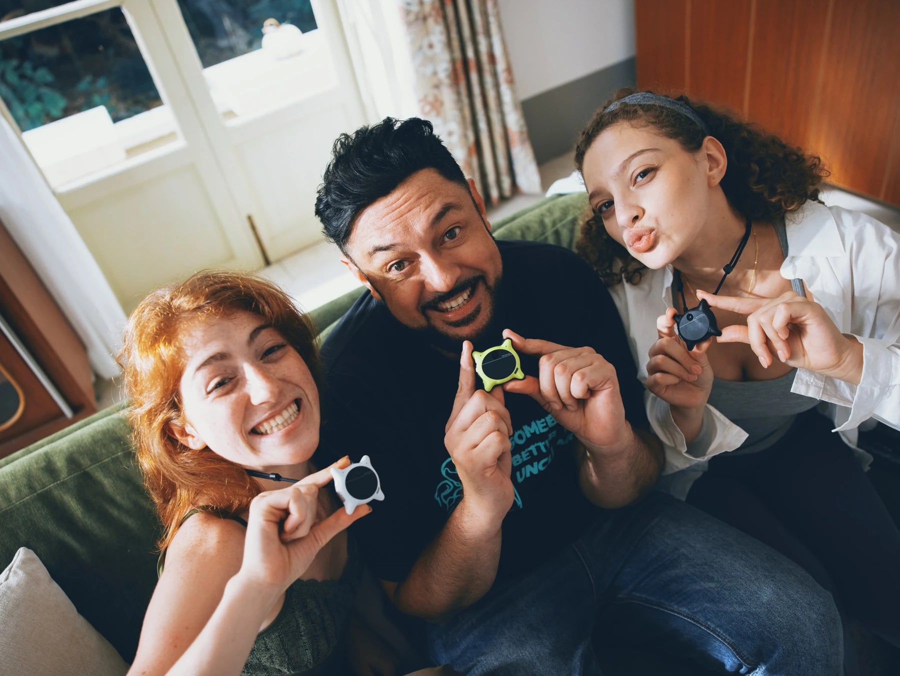 Three people holding Looki devices in a naturally lit room